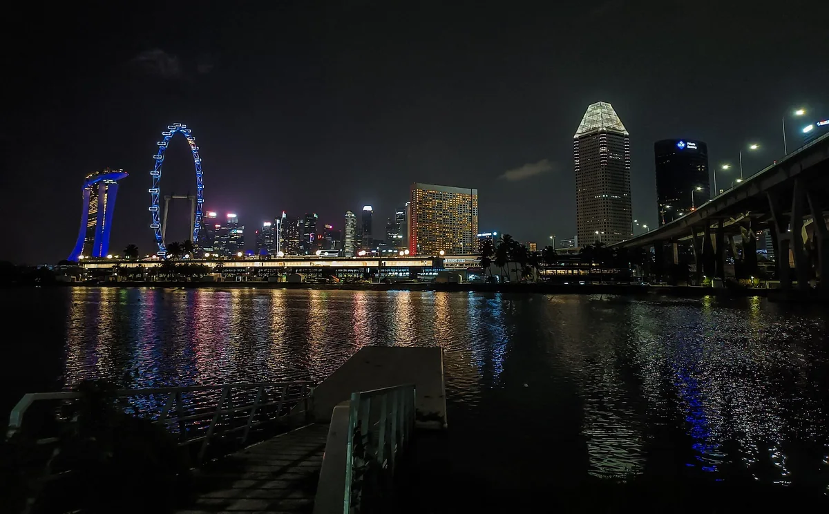 新加坡河口夜景，远处可见摩天观景轮与滨海湾灯光倒影
